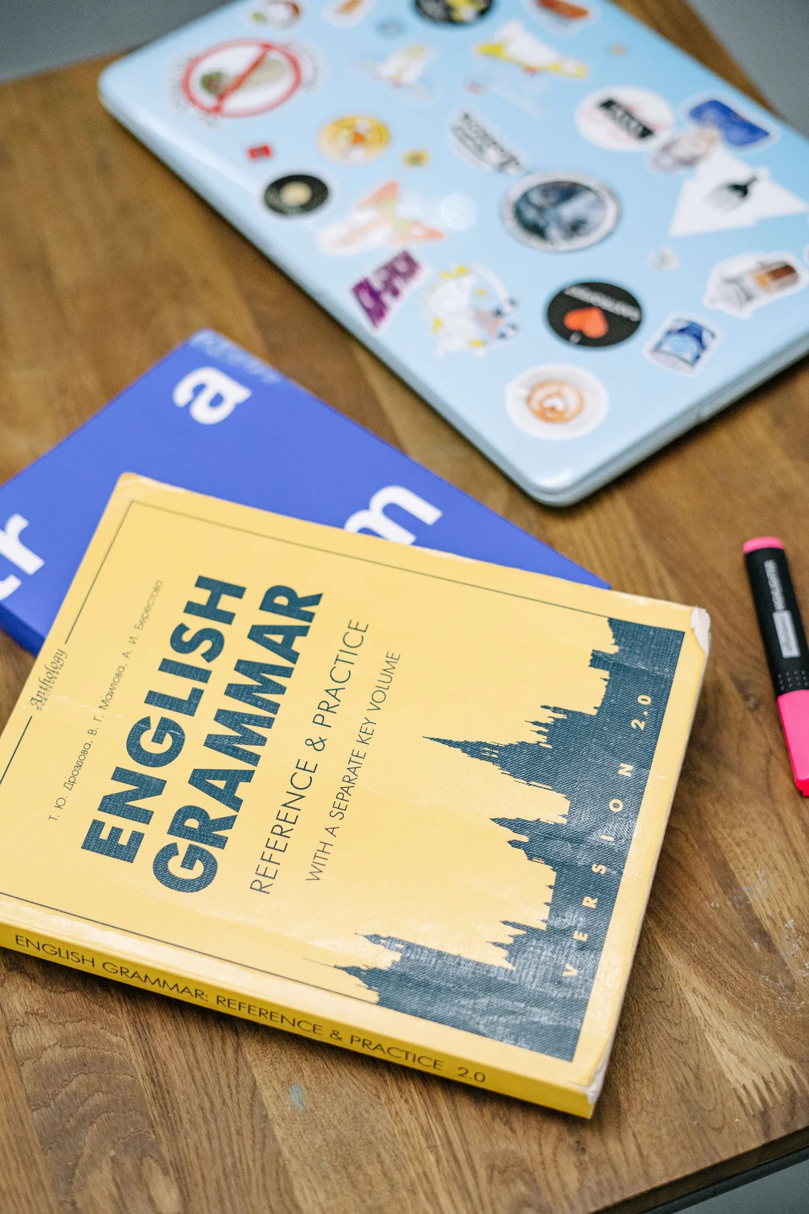 Un manuel de grammaire anglaise posé sur un bureau à côté d'un ordinateur portable.