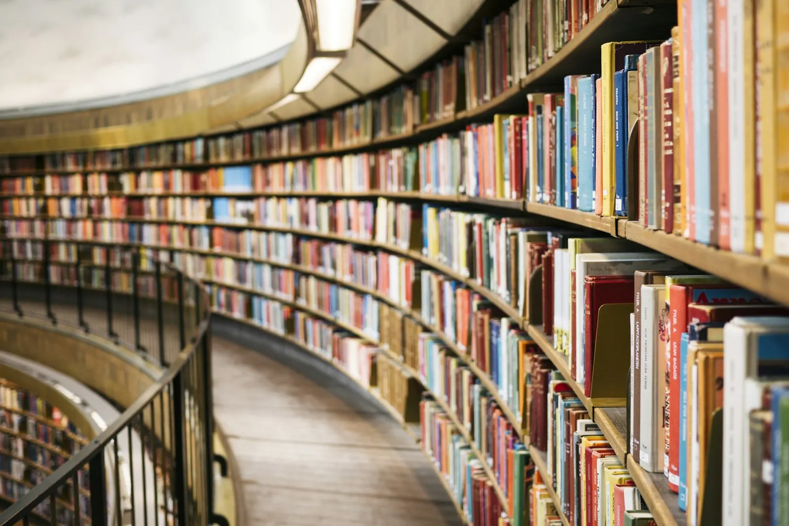 A stack of books on a light wooden shelf, viewed from the front.