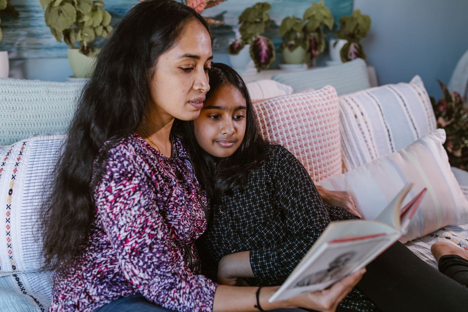 Mother and daughter reading together on a couch