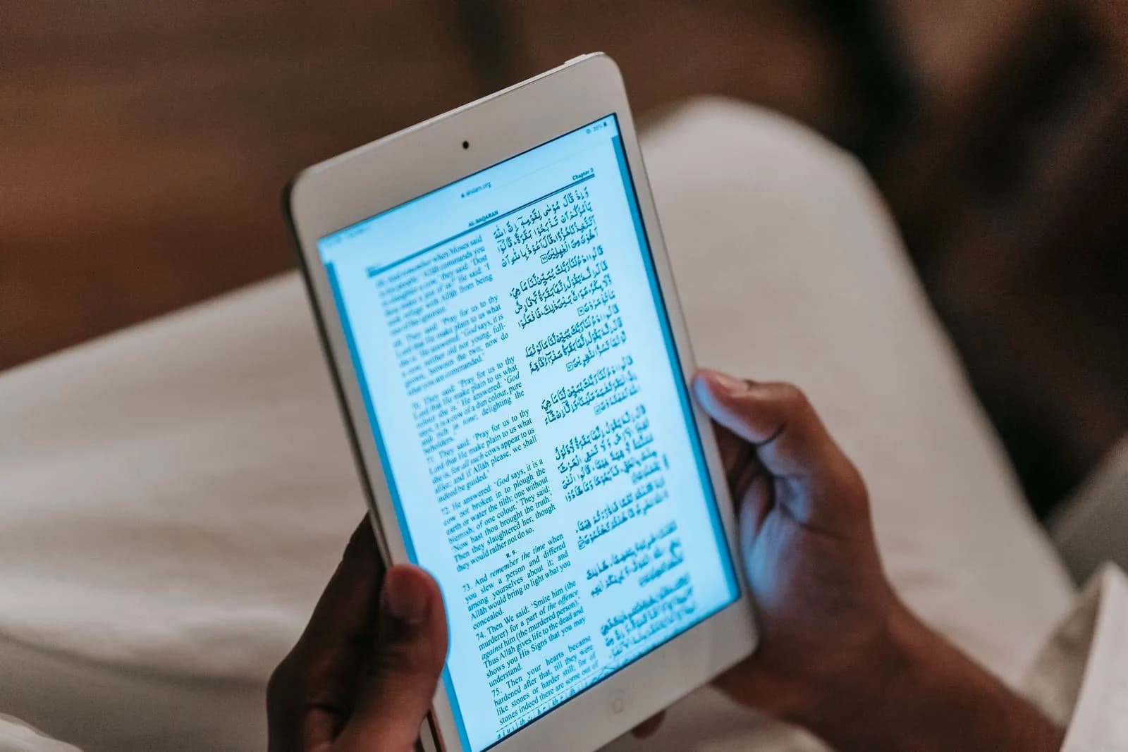 Une personne lisant un livre sur une tablette, comparant lecture numérique et papier.