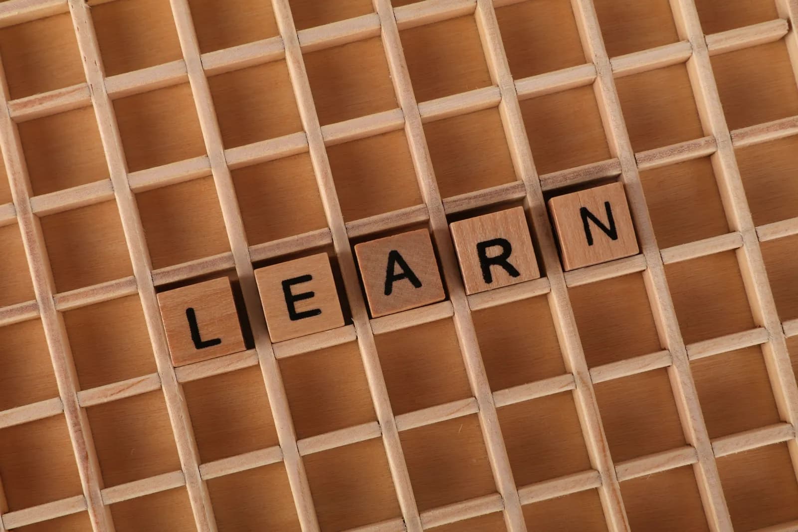 Des lettres en bois formant le mot LEARN sur une table en bois.