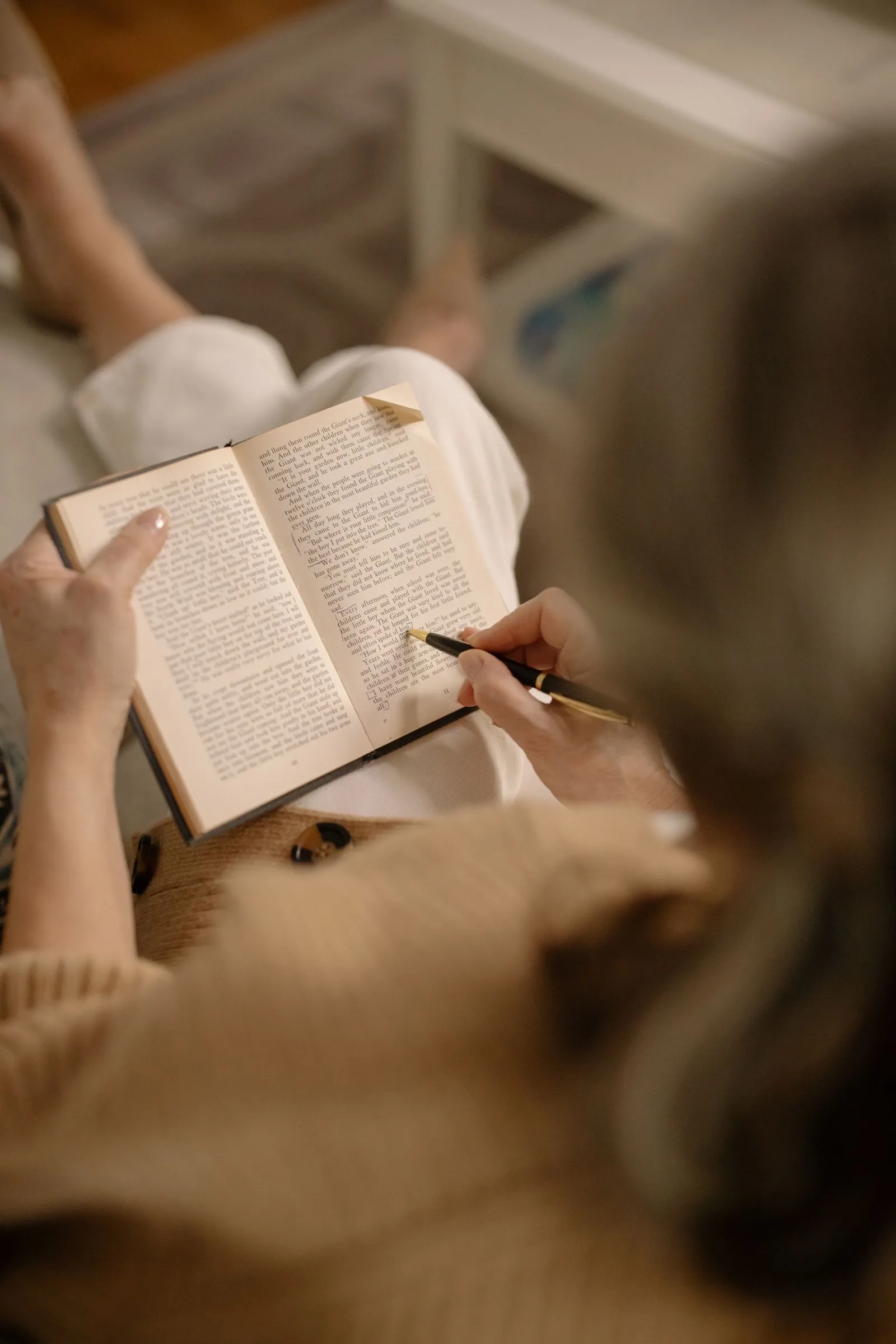 A person deeply focused on reading a book, without a separate dictionary open next to them.