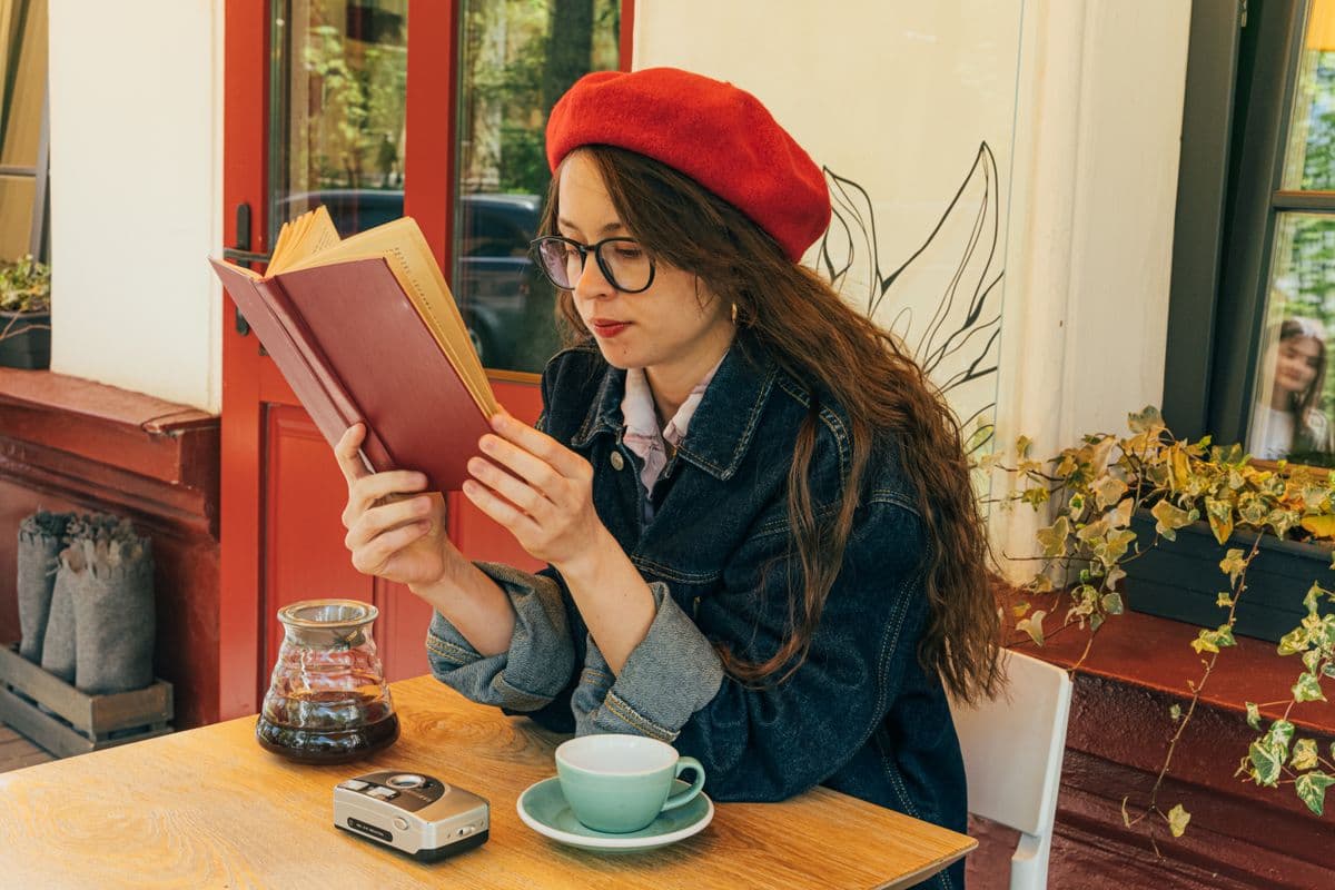 Person smiling, enjoying a book at a coffee shop