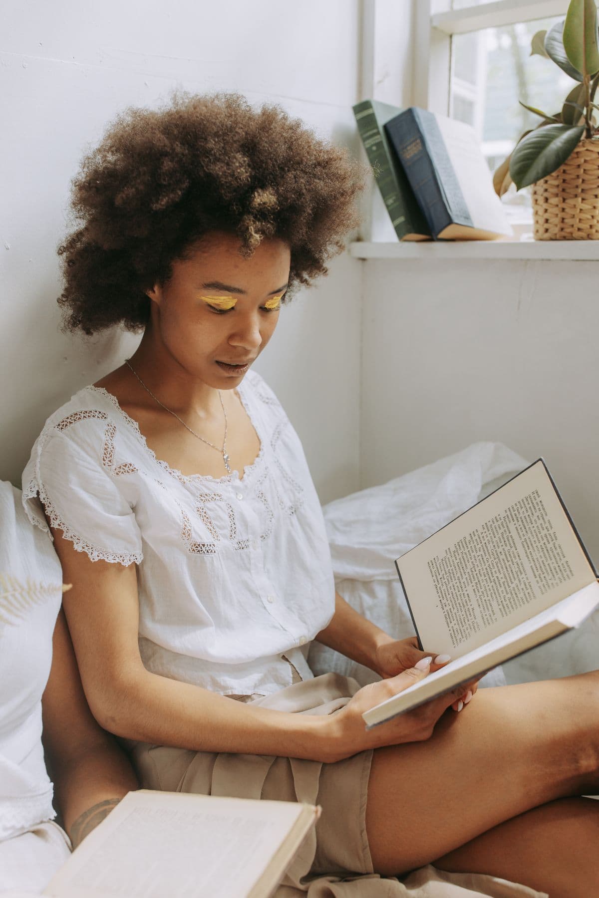 Person reading a book by a window, bathed in natural light