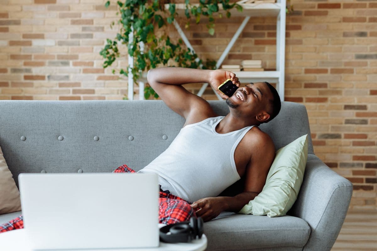 Person relaxed on their couch, checking an app on their phone